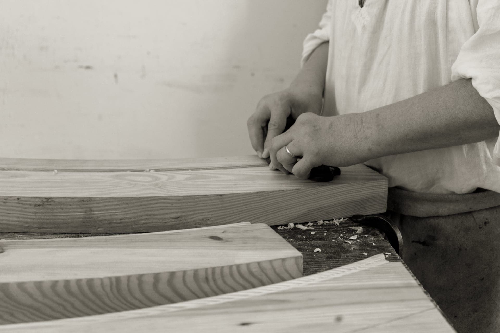 A woodworker planing a board by hand in a workshop