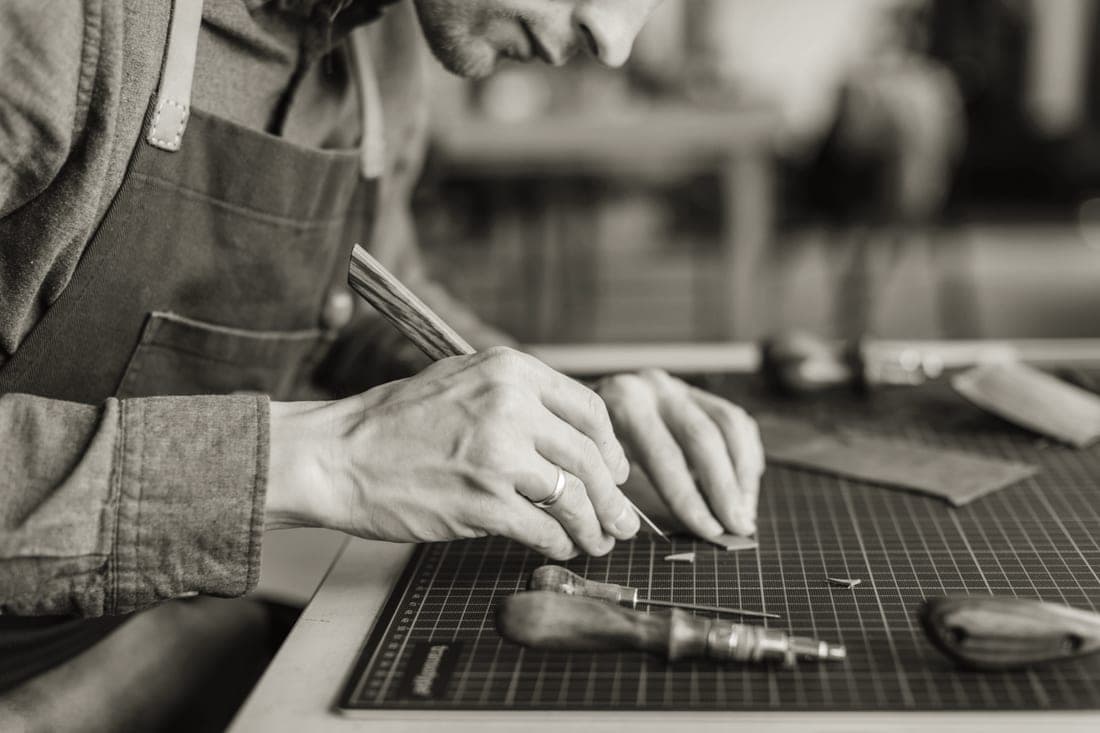 Close-up of full grain leather goods on a workbench showing grain and stitching